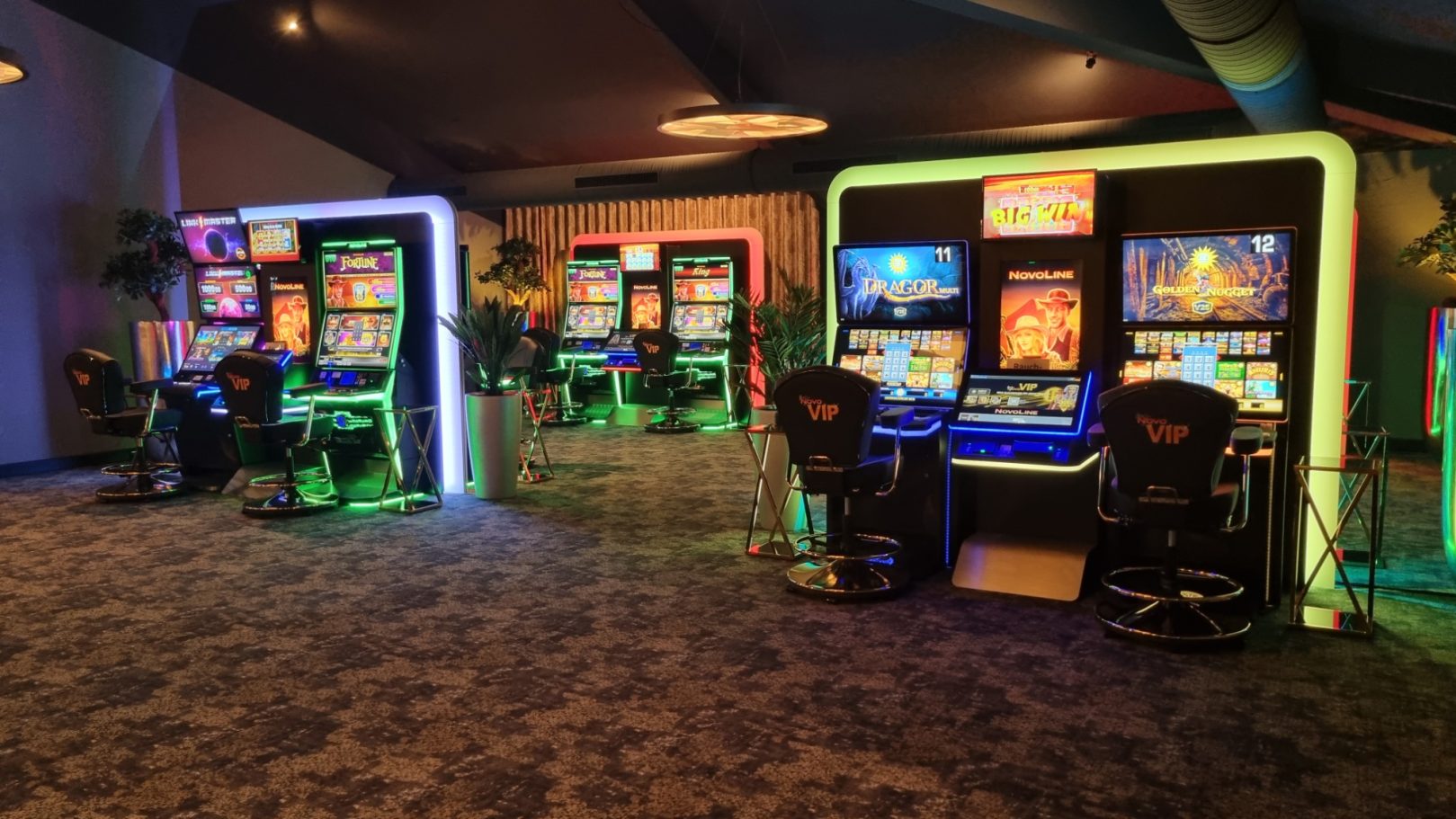 Spielhalle mit mehreren Spielautomaten und bunter Beleuchtung.